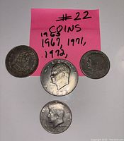 Front view of four coins dated 1963, 1967, 1971, and 1972 with a pink note listing these years.