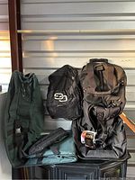 Photo showing both green Datrek golf bag and black golf glove bag on wheels, displayed hanging against a wall.