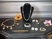 Full assortment of jewelry pieces arranged on a table including necklaces, bracelets, clip-ons, and pin.