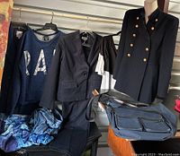 Full lot showing multiple items hanging on rack including navy Lauren jacket with gold buttons, RAD sweatshirt, black blazer, black and white top, pants, and bag.
