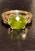 Front view of the 10K gold ring showing the faceted oval green stone and detailing on the band.