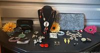 Full lot overview showing jewelry assortment with sunglasses cases, cosmetic bag, and decorative flowers