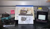 Full shot of several vintage electronics items including boxed Ventura telephone, Rhapsody TV/radio clock, and others on display.