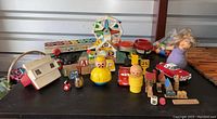 Wide view of the entire toy collection showing various items described including plastic toys, wooden miniature buildings, signs, and characters.