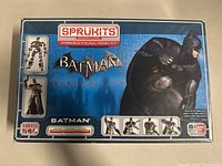 Front view of box showing Batman figure in crouching pose with blue background, SpruKits logo and Batman Arkham City branding.