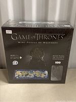 Front view of the Game of Thrones Mini Puzzle of Westeros box, sealed in shrink-wrap, shows Iron Throne image and puzzle map.