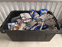 Overview of large black bin filled with multiple Hot Wheels cars still in packages.