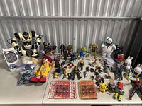Wide view of the toy lot showing various action figures, collectibles and large robot toy on tabletop.