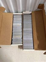 Two white cardboard boxes filled with stacks of trading cards, viewed from above.