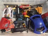 Top-down view showing the assortment of tools including drill, nail gun, hammer, rope, and battery charger.
