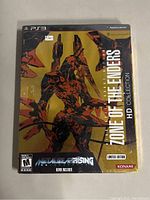 Front view of the sealed PS3 game Zone of the Enders HD Collection with orange and black robot on gold background and labels indicating limited edition and Metal Gear Rising demo.