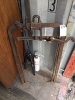 Full view of antique Beatty F14 hay fork standing against a wall next to a fire extinguisher and other items