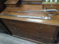 Full view of saber and scabbard laid out on wooden surface