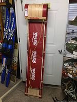 Full front view of the upright wooden Torpedo toboggan with Coca Cola red pad, showing length and condition.