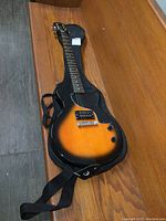 Full guitar in soft gig bag laid on wooden bench