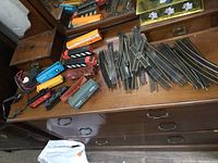 HO scale train set components arranged on a wooden dresser including multiple train cars and track pieces.