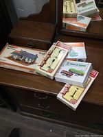 Photo showing multiple Tyco HO scale kit boxes and packages on wooden surface including light posts, trams, and Mas Place building kit.