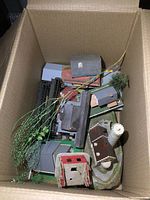 View inside the box showing multiple model railroad structures and artificial plants including silo, industrial and residential buildings.
