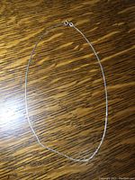 Full view of the sterling silver chain necklace placed on wooden surface, showing approximate length and clasp type.