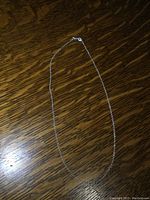 Full length view of the silver chain necklace on wood surface.