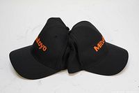 Two black nylon baseball hats with embroidered orange Mitutoyo logo, displayed front and side by side