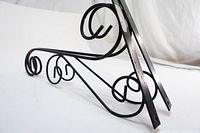 Two black wrought iron wall brackets laid flat showing the curved motif and design details.