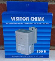 Front view of the product in packaging showing the 300D Visitor Chime device and text explaining it automatically rings with 'Ding Dong' or music melody on visitor detection.