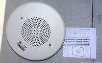 Close-up photo of one Siemens CS-4100-70 speaker strobe unit showing the perforated grille and marking, alongside printed installation instructions.