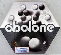 Top view of hexagonal Abalone board game box showing black and white marbles and game logo
