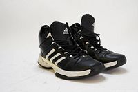 Pair of black and white Adidas basketball shoes angled left showing the side and top of shoes.