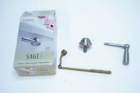 Three items: chrome toilet tank lever handle, brass-tone connecting rod, chrome mounting hardware, with Moen Inspirations Sage box in background.