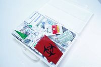 Open view of the first aid kit showing organized contents inside including scissors, various bandages, antiseptic wipes, gauze, tape, and biohazard bag.