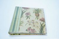 Photo album closed showing floral and pineapple designs on cover