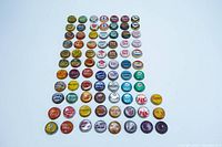 Full layout of 80 vintage and antique bottle caps, colorful and arranged in rows on white background.