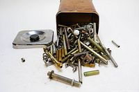 Photo showing metal can with nuts, bolts, and small metal parts spilling out.