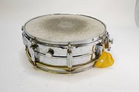 Full view of vintage 8-lug chrome steel snare drum showing metal shell, chrome finish, drum head, and yellow original drum key holder.