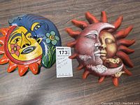 Pair of colorful sun and moon wall art pieces on a table with a lot tag, showing the full front design and detail.