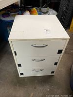 Front view of white 3 drawer end table showing design, color, and wear.