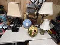 Overview of all eight table lamps on a white table, showing various styles and four lamps with shades
