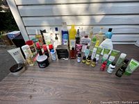 Wide view of the full assortment of shampoos, creams, perfumes, and personal care products arranged on a wooden table outdoors.