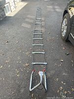 Full length of the metal emergency escape ladder stretched out on the ground showing metal rungs and chain sides with hooked top end.