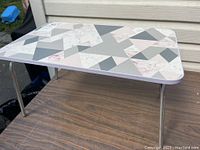 Side angled view of folding bed tray showing geometric patterned surface and foldable metal legs