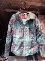 Full front view of the ladies winter jacket showing the plaid design and front zipper.