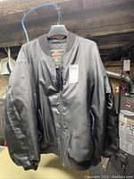 Black Windriver men's jacket hanging on a black hanger with visible front and zipper.