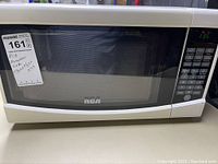 Front view of white RCA microwave oven with black window and brand name visible