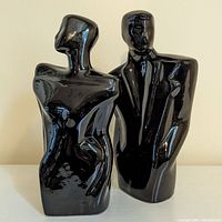 Front view of pair of ceramic fashion figures in black, male and female busts with glossy finish