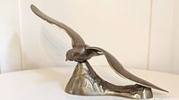 Front view of the brass seagull sculpture showing the outstretched wings and the detailed textured base.