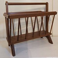 Photo of the entire wooden mid century magazine rack showing the front with diamond pattern slats and sturdy handle, viewed against a white background