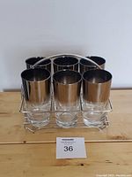 Front view of 6 glasses with metallic luster band in metal wire caddy on wooden surface