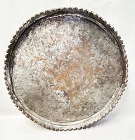 Front view of large round copper tray showing etched central design and scalloped edge